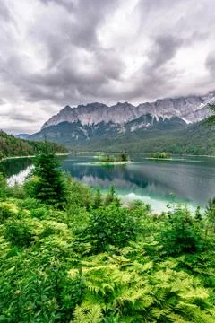 Small islands with pine-trees in the middle of Eibsee lake with Zugspitze mou Fotos de archivo