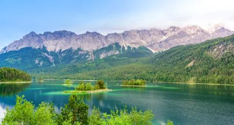 Small islands with pine-trees in the middle of Eibsee lake with Zugspitze mou 库存照片