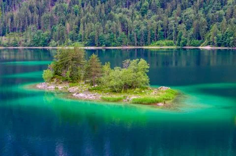 Small islands with pine-trees in the middle of Eibsee lake with Zugspitze mou Fotos de archivo