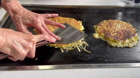 Small Japan restaurant an elderly chef cooks okonomiyaki side by side Stock Footage 324020609