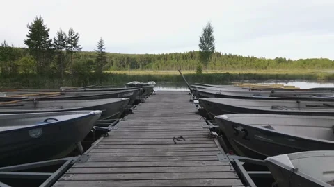 Small jetty and rowing boats in a mirrorlike lake one sunny morning Stock Footage 145869583