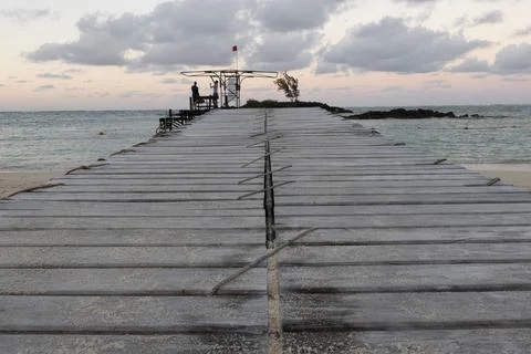 Small jetty or pier with clouds and man silhouetted just after sunset Foto stock