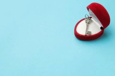 Small key from the heart in a red gift box on a bright blue background close- Stock Photos