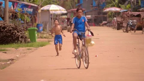 A small khmer boy is running down the road in the famous fisherman village Stock Footage 305668895