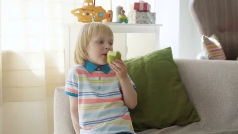 Small kid boy bite juicy fresh green apple as a healthy snack wishing to be Stock Footage 77906358