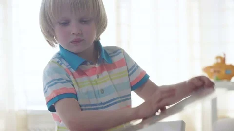 Small kid boy opens and examines book with colorful illustrations with bright Stock Footage 78611134