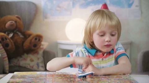 Small kid boy opens and examines book with colorful illustrations with bright Stock Footage 78611280