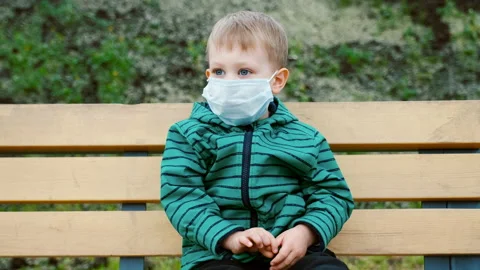 Small kid boy wears face mask looking funny, prevention for coronavirus COVID-19 Video stock 133624576