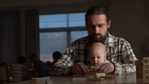 Small Kid newborn with Dad playing tiny jenga her parents at table, jenga tower Video stock 172505076