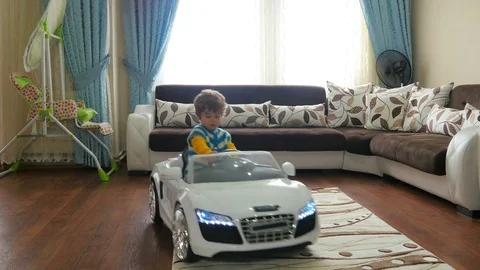Small kid playing toy batery car at home Stock Footage
