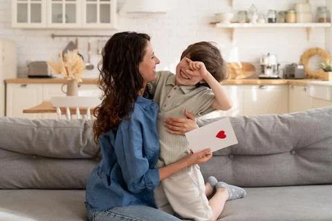 Small kid present mom greeting card with heart on mother day, birthday Stock Photos