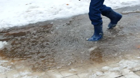 Small kid in waterproof boots walking on puddle Stock Footage 100635546