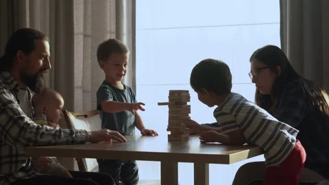 Small Kids Children playing tiny jenga with her parents at table, jenga tower Stock Footage 172382122