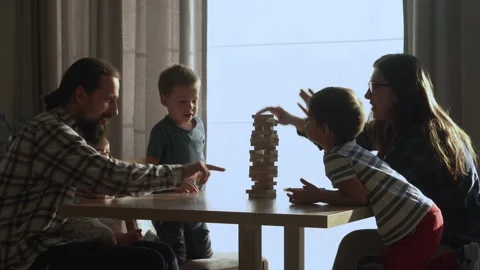 Small Kids Children playing tiny jenga with her parents at table, jenga tower Video stock 172455922