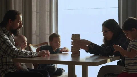Small Kids Children playing tiny jenga with her parents at table, jenga tower Video stock 172505209