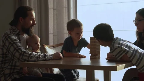 Small Kids Children playing tiny jenga with her parents at table, jenga tower Stock Footage 172505316