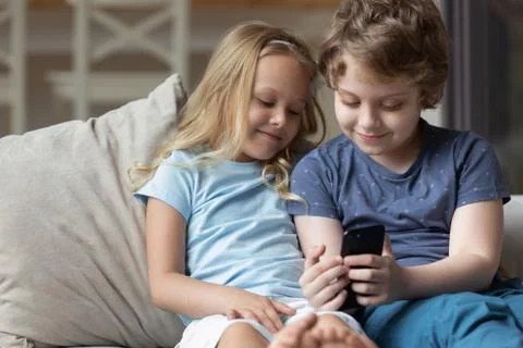 Small kids have fun using cellphone together Stock Photos