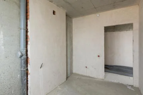 Small kitchen in a new building, bare concrete and plastered walls, communica Foto stock