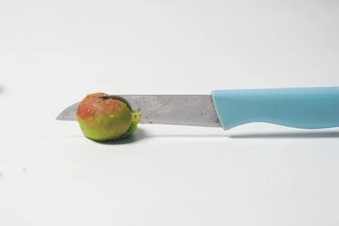 A small knife cutting into an apple-shaped cookie placed on a bright white .. Stock Photos