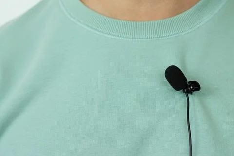 Small lavalier microphone or mic buttonhole on a man's t-shirt closeup Stock Photos