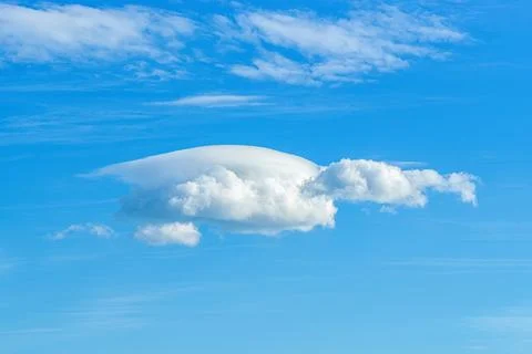 Small lenticular cloud against translucent cirrus clouds high in a blue sky Stock Photos