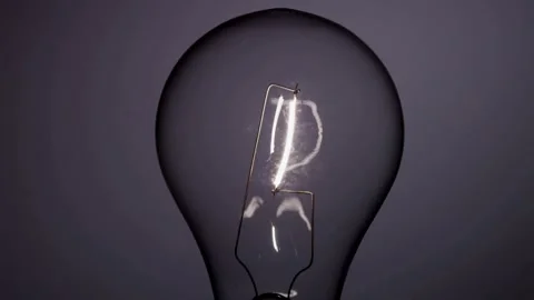 Small light bulb filament glowing briefly in the dark Stock Footage 329657261