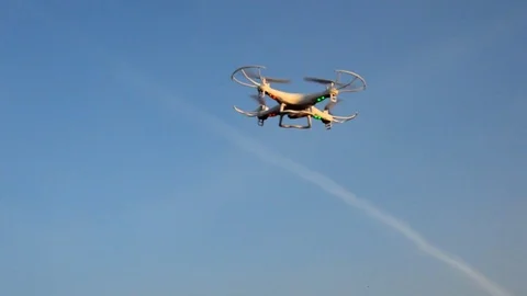 Small light drone flying in the wind with jet traces on the sky Stock Footage 84819693