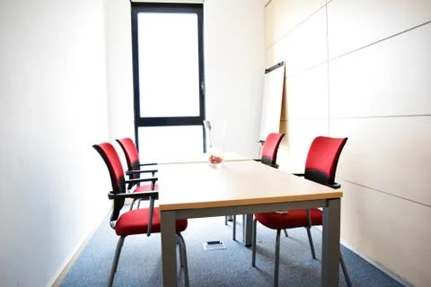 Small light empty office room with table and red chairs Foto stock