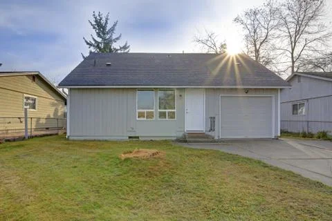 Small light grey one level home exterior with car garage. Stock Photos