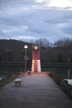 Small lighthouse on harbor jetty at dusk. Stock Photos