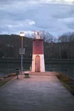 Small lighthouse on harbor jetty at dusk. Stock Photos