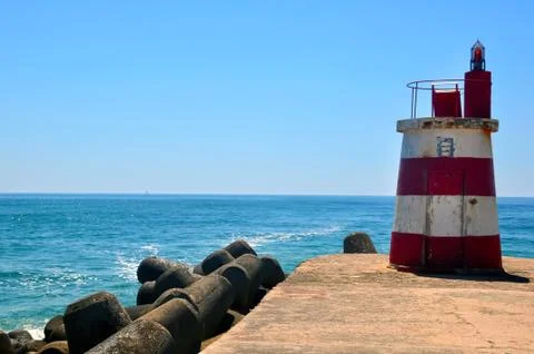 Small lighthouse on the ocean shore Stock Photos