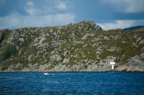 Small lighthouse by steep cliffs by the sea Stock Photos