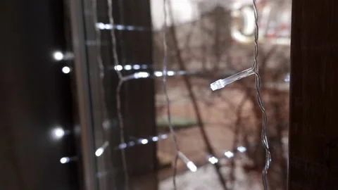 Small lights glowing with white light hang on the window. 4K Stock Footage 165819052