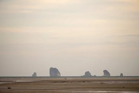 Small limestone islands beyond sandy tidal beach Thailand Stock Photos