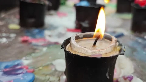 A small lit devotional candle in the foreground, among several others Stock Footage 221113040