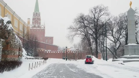 A small loader excavator bobcat removes snow from the sidewalk near the Kremlin Stock Footage 162697900
