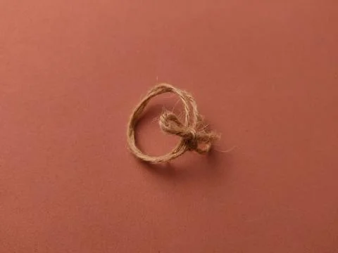 A small loop of natural brown twine with a simple knot sits centered on a s.. 写真素材