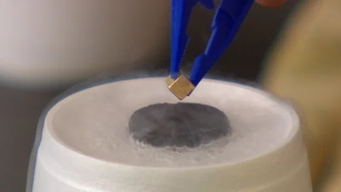 Small magnet levitating above a superconductor cooled by liquid nitrogen Stock Footage 99055942