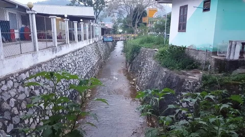 Small man made gutter stream between houses, wooden bridge, Sam Neua, Laos Vidéo 76793160