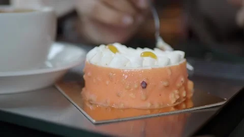 Small mango mousse cake topped with whipped cream and yellow fruit topping Stock Footage 337919069