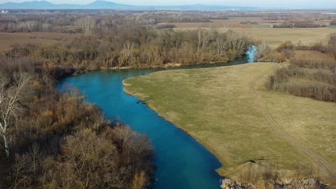 Small meandering river in the plain - drone shot moving forward Stockbeeldmateriaal 125120921