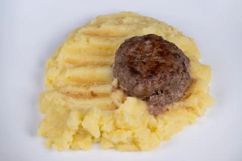 Small meat serving. Compact portion of browned meat placed over textured mashed Stock Photos