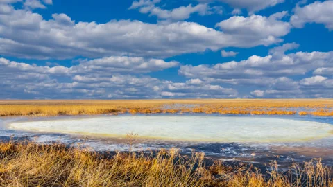 Small melting lake with floating ice, spring prairie scene Stock Footage 138618617