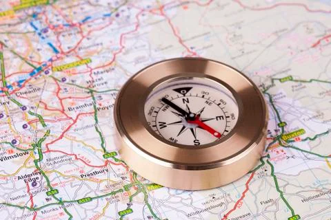 Small metal compass on map Stock Photos
