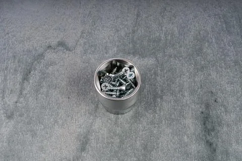 Small metal container filled with assorted screws on gray surface Stock Photos