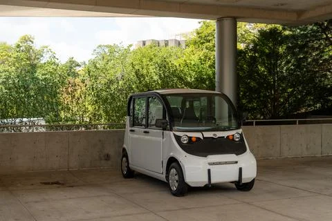 Small micro electric car parked on a city street, sustainable urban transport Stock Photos