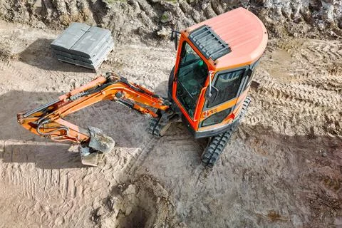 A small mini excavator is working on a construction site. Close-up. View from Stock Photos