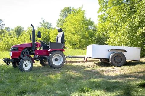 Small mini red modern new tractor with trailer standing at farm, field, nat.. Stock Photos