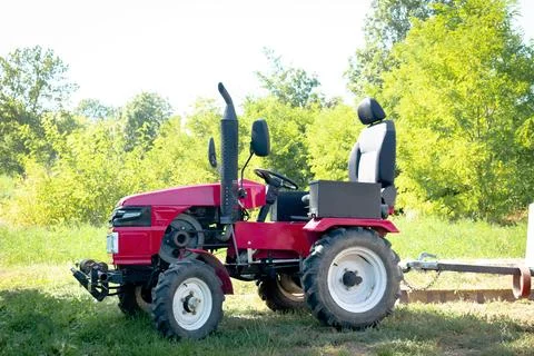 Small mini red modern new tractor standing at farm, field, nature countrysi.. Stock Photos